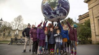 group of people touching a suspended model of the globe