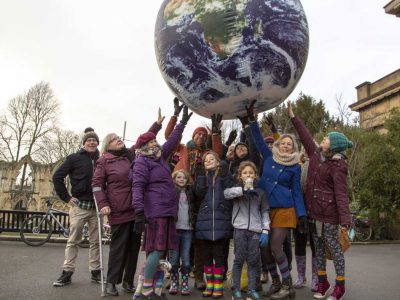 group of people touching a suspended model of the globe